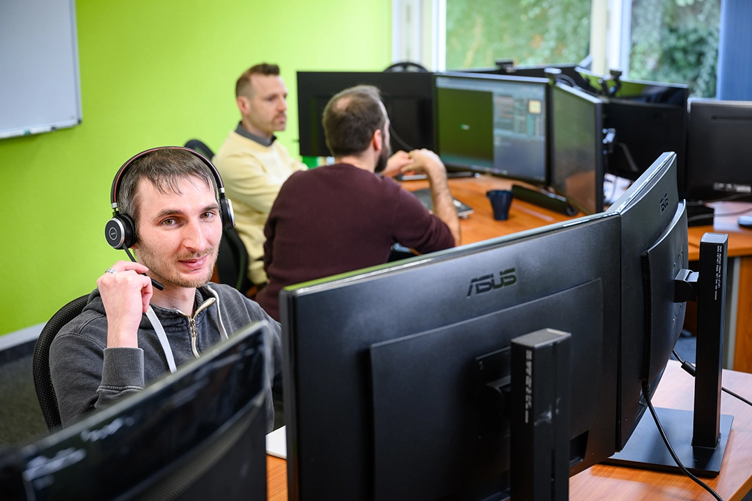 IT-Mitarbeiter arbeiten konzentriert an mehreren Bildschirmen im Büro.